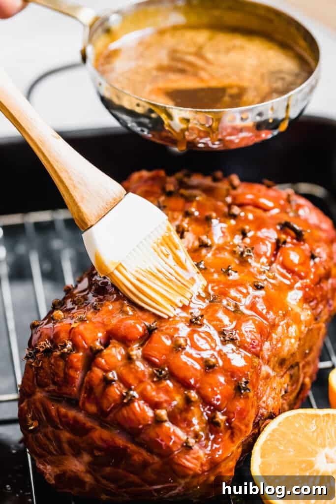 Pouring and Brushing Brown Sugar Glaze Over the Ham, creating a rich, glossy coating.