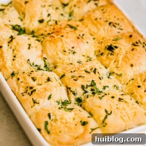 Twelve freshly baked Soft Parmesan Dinner Rolls in a pan, ready for serving.