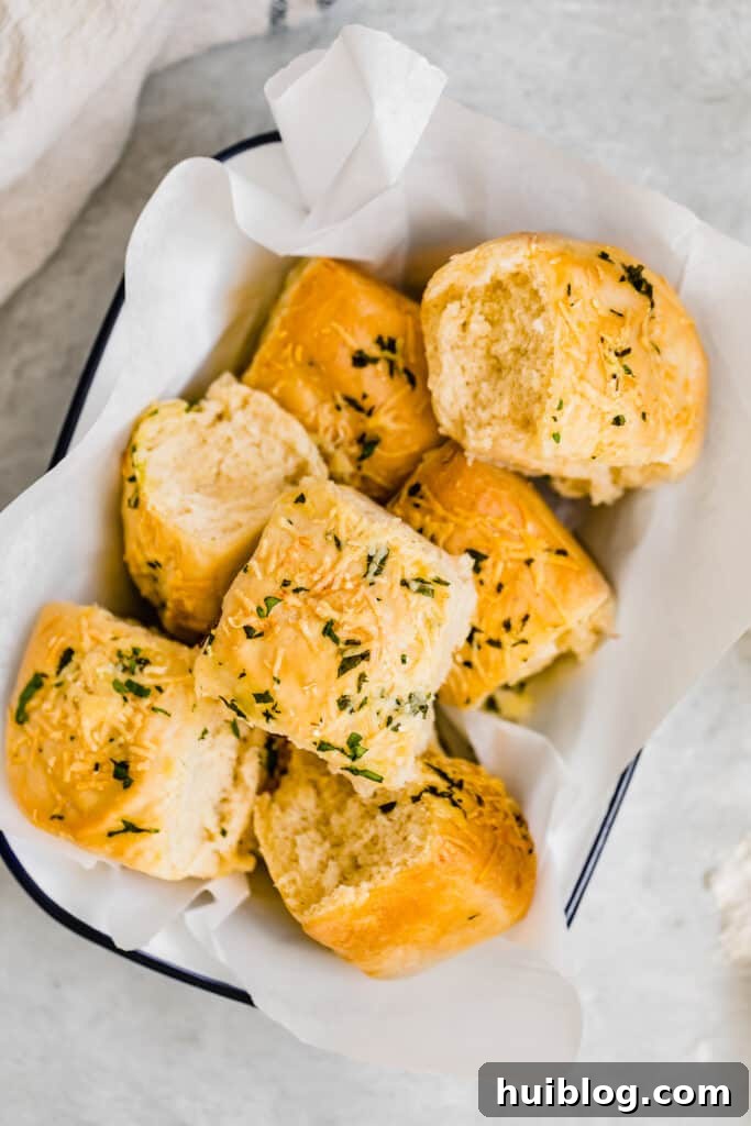 Seven Soft Parmesan Dinner Rolls neatly arranged in a wicker basket lined with white tissue paper, ready for serving.