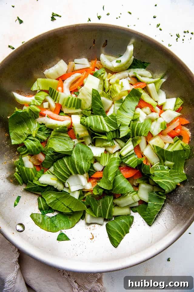 stir frying bok choy, onions, and bell peppers in a skillet