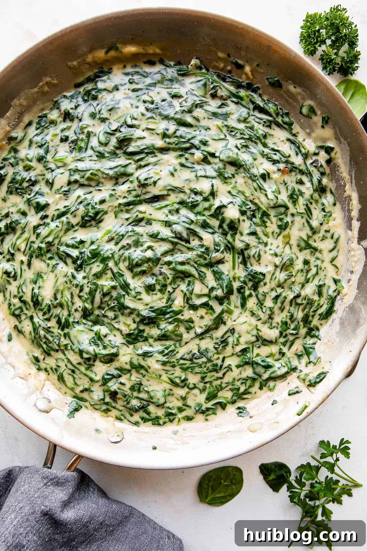 Close-up overhead picture of creamed spinach simmering in a large skillet, showing its rich, creamy texture and vibrant color.