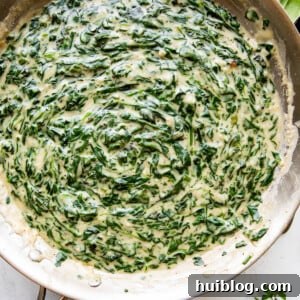 overhead picture of creamed spinach cooking in a large skillet.