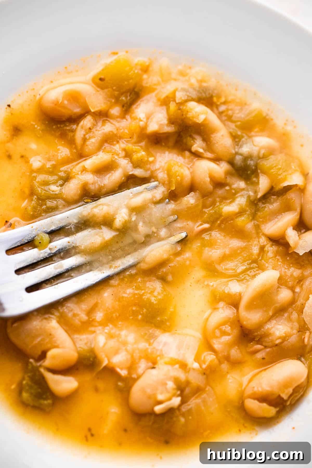Mashing cannellini beans with a fork to naturally thicken the chicken chili.