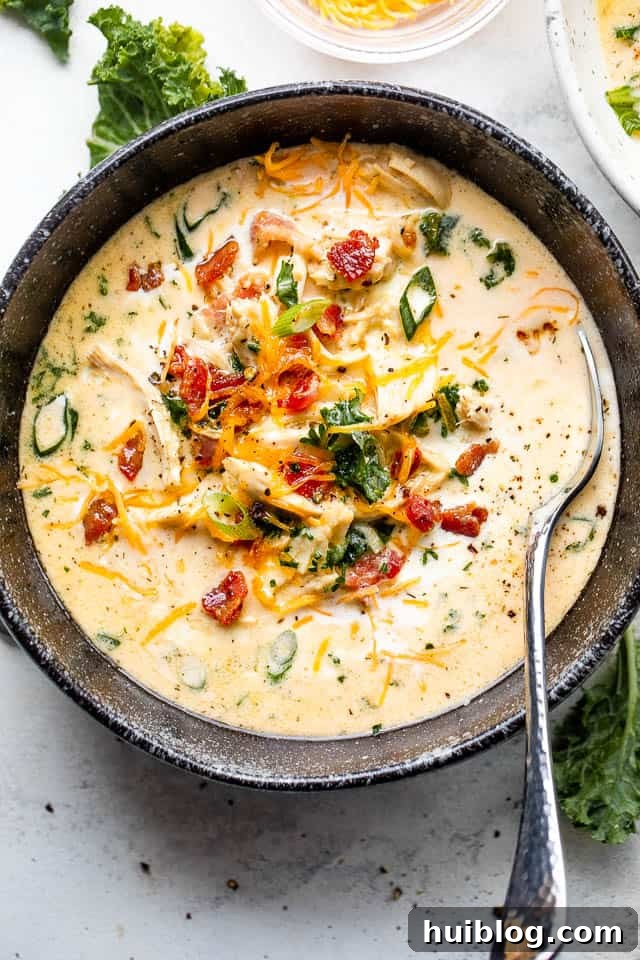 Creamy Crack Chicken Soup in a black bowl served with a spoon, garnished with bacon and scallions.