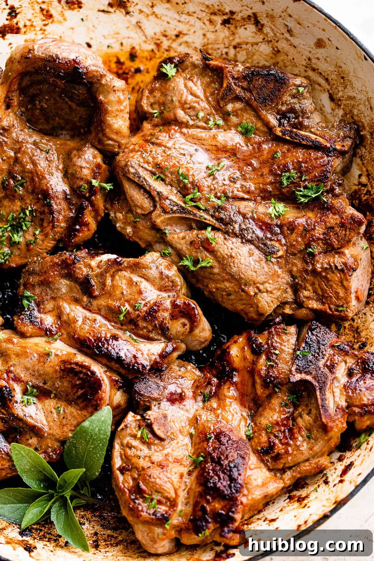 Close-up shot of a cooked lamb chop garnished with a sprig of fresh mint, emphasizing its juicy interior.