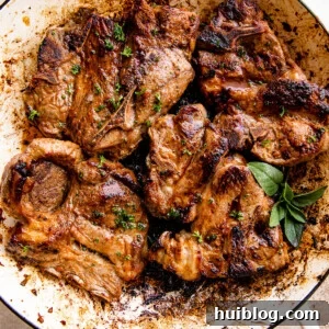overhead shot of a white cast iron skillet with cooked lamb chops inside