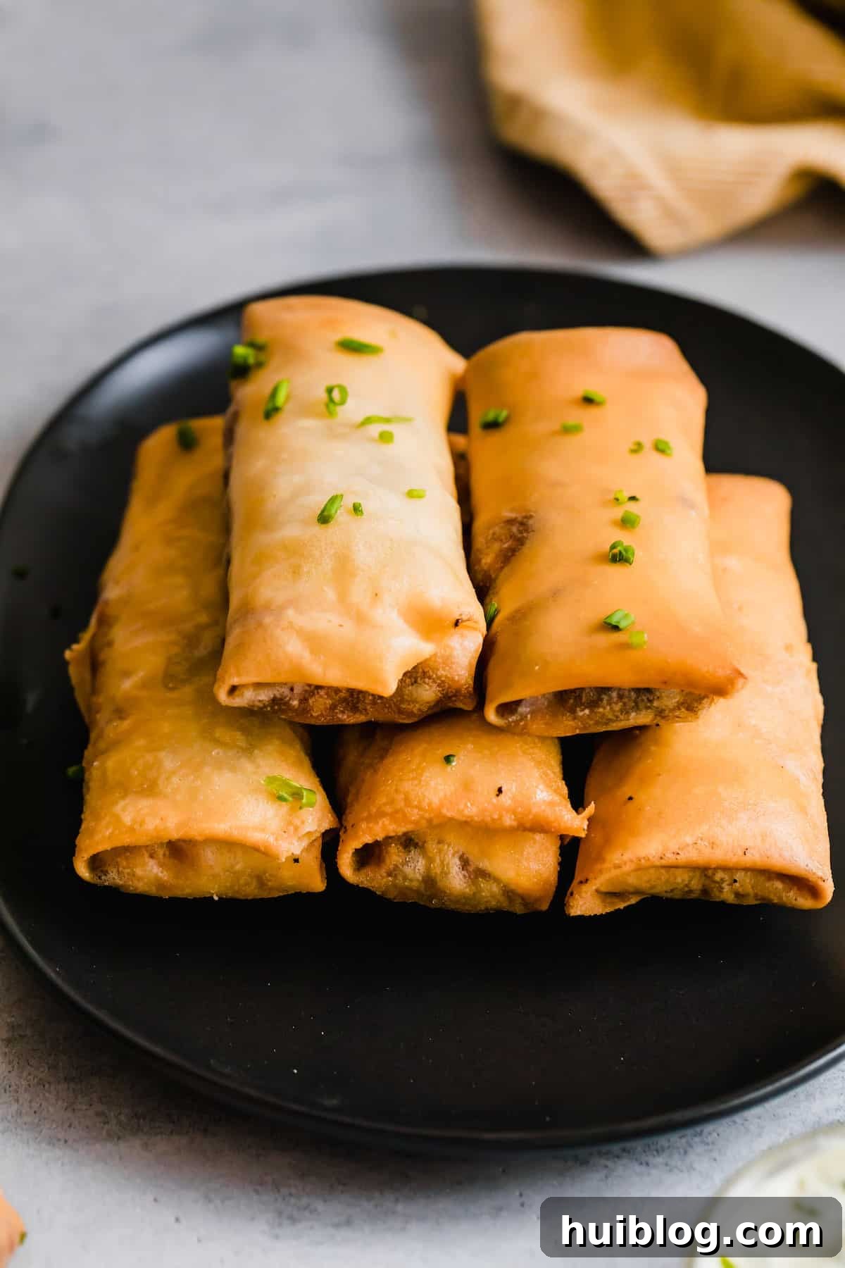 Cheesecake Factory Inspired Tex-Mex Egg Rolls 12 Five Crispy Egg Rolls Piled Neatly on a Shiny Black Plate, Ready to Serve