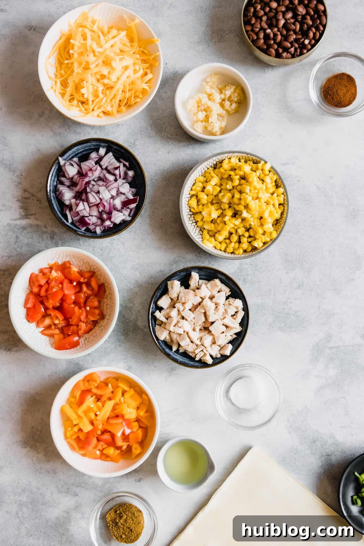 Cheesecake Factory Inspired Tex-Mex Egg Rolls 4 Shredded Cheese, Diced Tomatoes, Diced Chicken and the Rest of the Egg Roll Ingredients Neatly Arranged on a Countertop