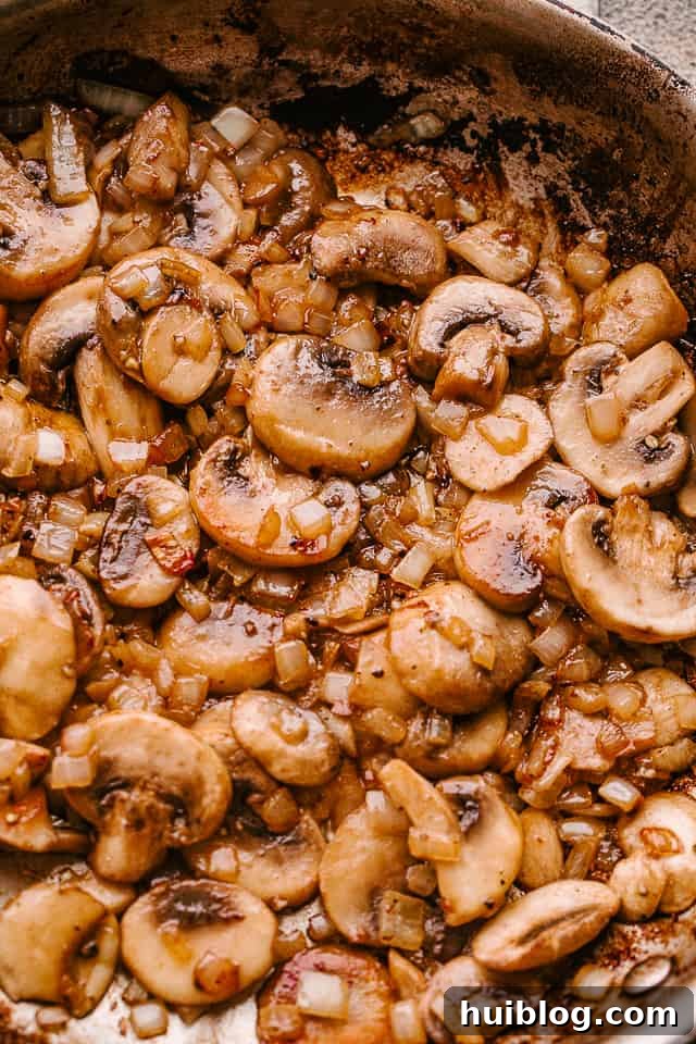 Mushroom gravy being prepared in a skillet with onions and garlic.