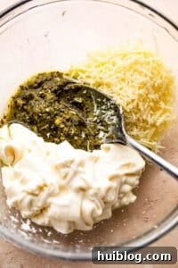 Zesty Caprese Chicken Bake 9 Mixing basil pesto, mayonnaise, and parmesan cheese in a bowl.