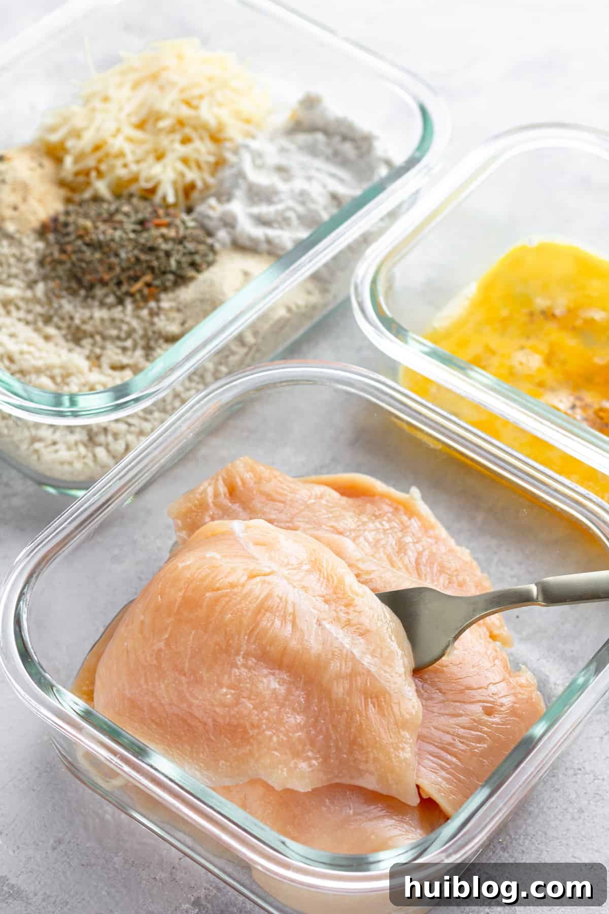 Ultimate Air Fryer Chicken Parmesan 5 Three Glass Containers on a Counter – One Containing Raw Chicken, One Containing the Egg Mixture and One Containing the Un-Combined Breading Mixture