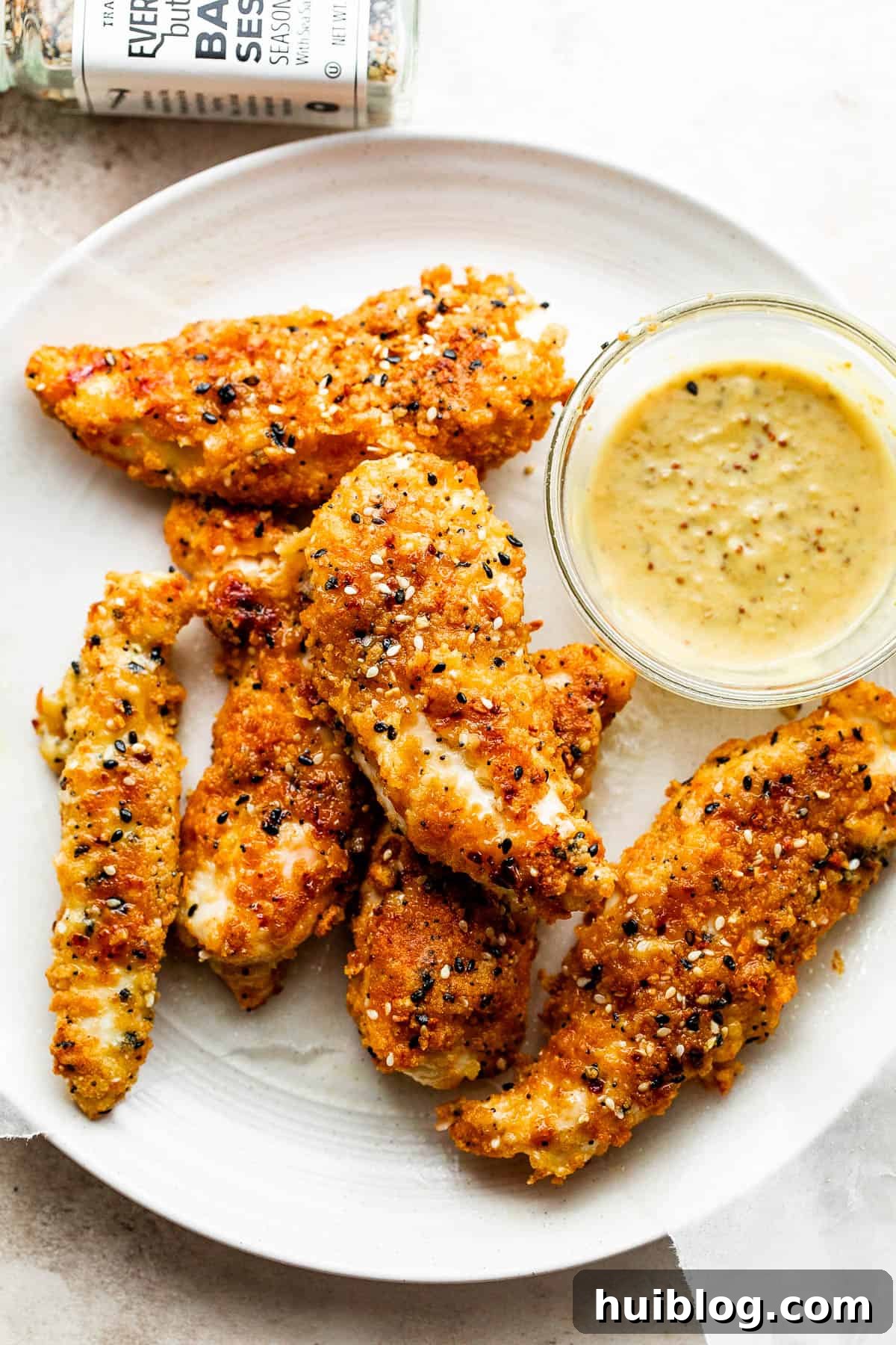 Everything Bagel Crusted Chicken Tenders 2 Everything Bagel Chicken Tenders arranged on a round plate and served with honey mustard dipping sauce