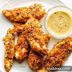 Everything Bagel Chicken Tenders arranged on a round plate and served with honey mustard dipping sauce