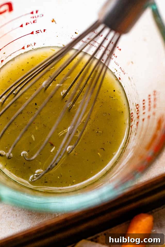 Zesty Grilled Vegetable Medley 5 A whisk vigorously mixing homemade lemon vinaigrette in a glass bowl, showcasing the emulsification of oil, lemon juice, and herbs.