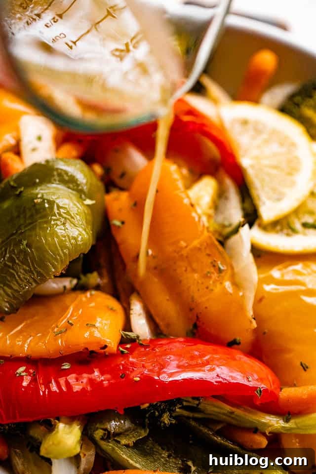 Zesty Grilled Vegetable Medley 6 Lemon vinaigrette being poured over a bowl of freshly grilled bell peppers and other vegetables, adding a glistening finish.