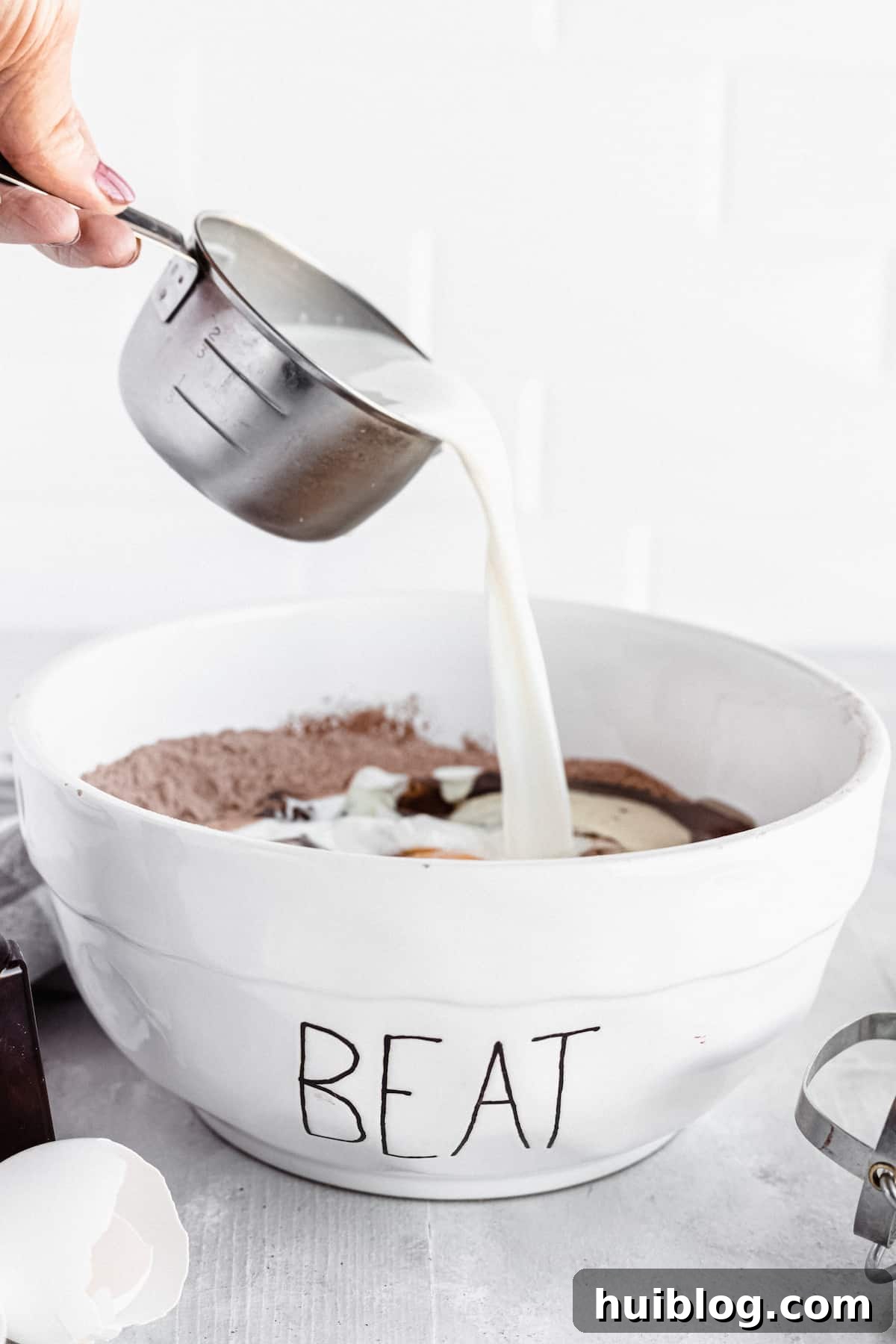 Milk being added to a bowl of cake ingredients