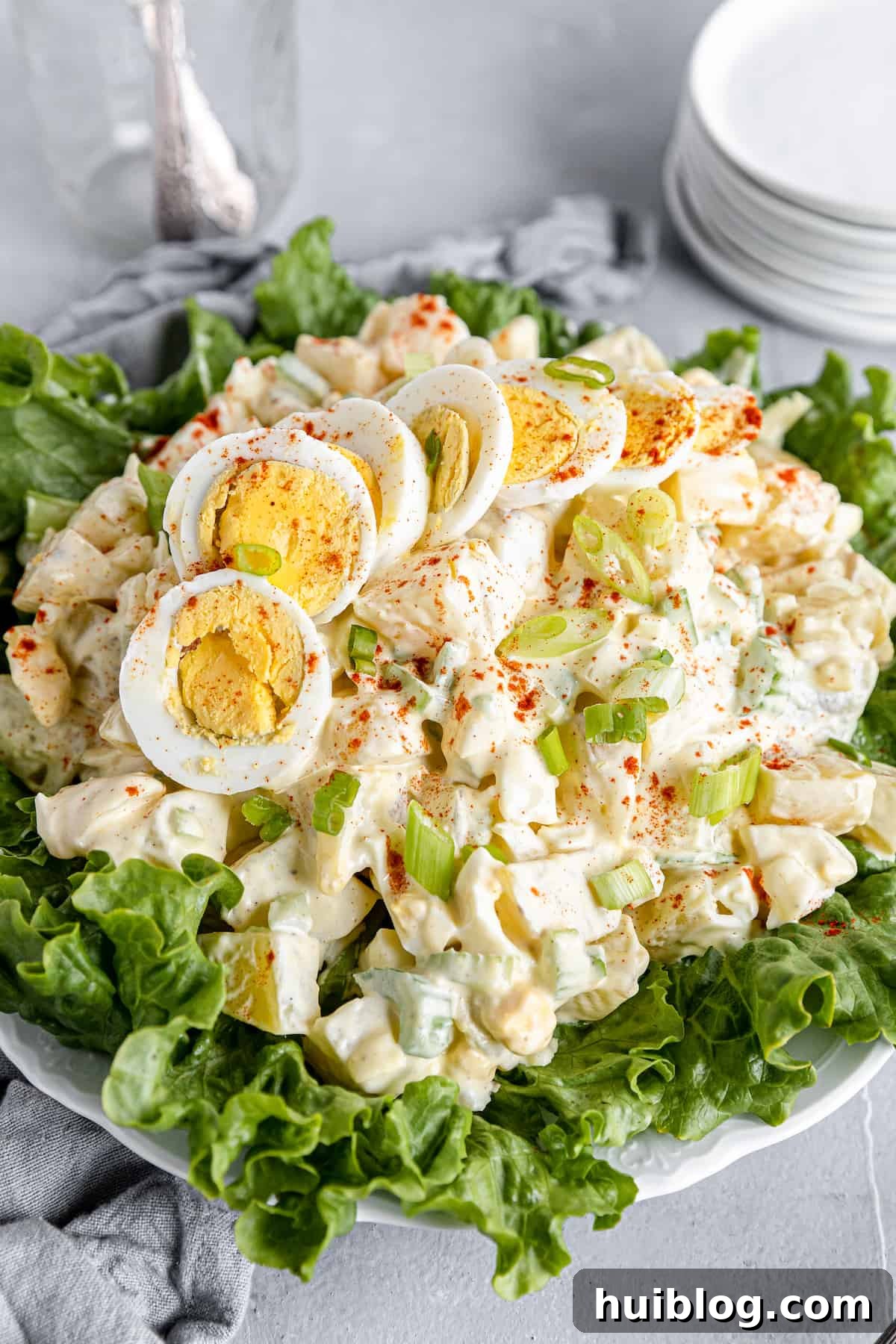 All-American Potato Salad 2 A Big Plate of Salad with Smaller Plates Stacked in the Background, showcasing a creamy American Classic Potato Salad.