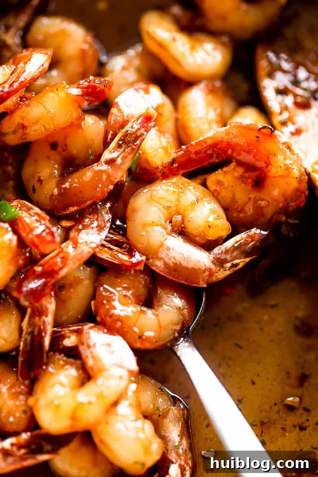 Honey Garlic Shrimp are cooked in the most delicious sauce. A quick, easy shrimp recipe that uses only one skillet, 5 ingredients, and 20 min! A spoon stirring honey garlic shrimp in a pan, showcasing the rich glaze.