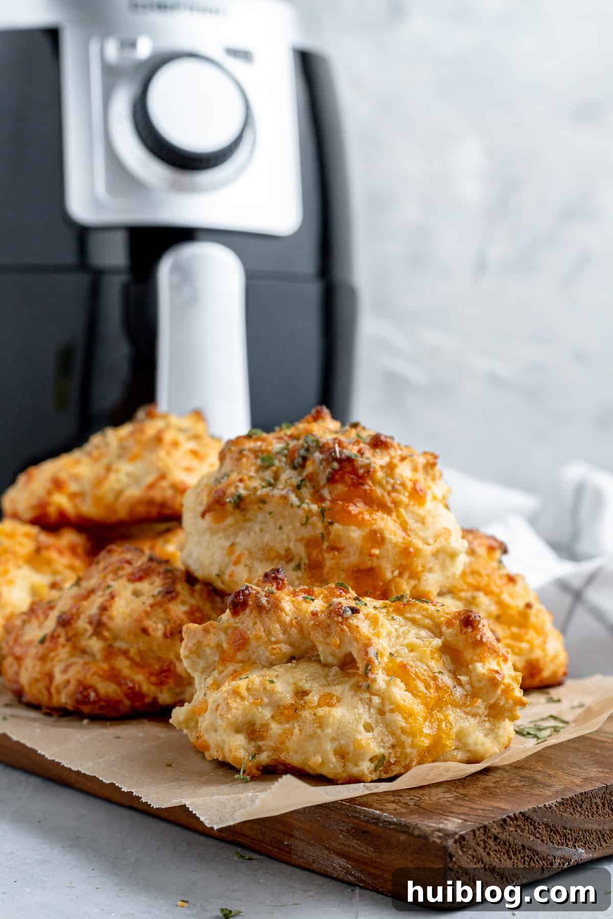 A pile of homemade Red Lobster biscuits on a cutting board, with an air fryer in the background