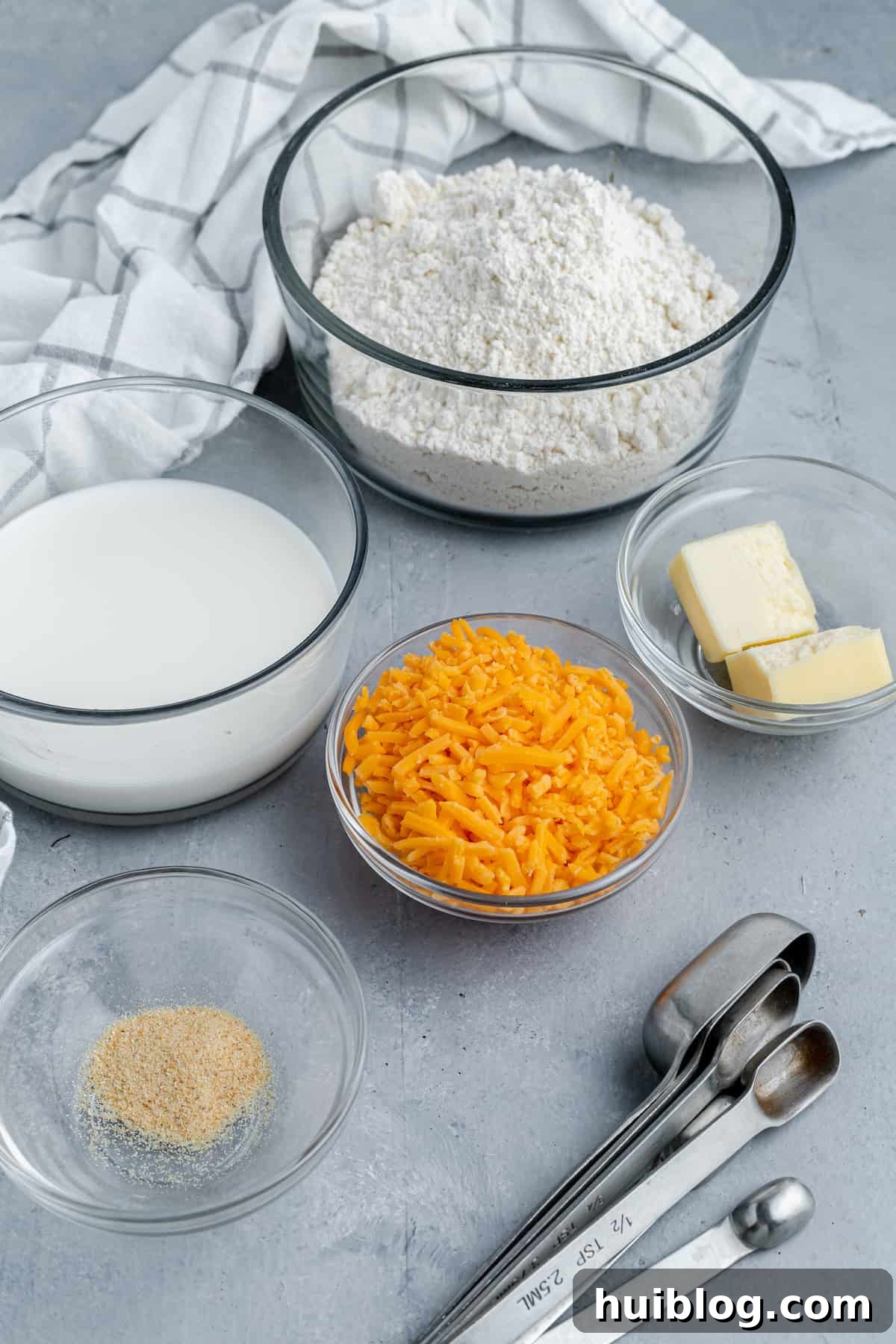Bisquick, butter, garlic powder, shredded cheese, and other recipe ingredients on a gray countertop