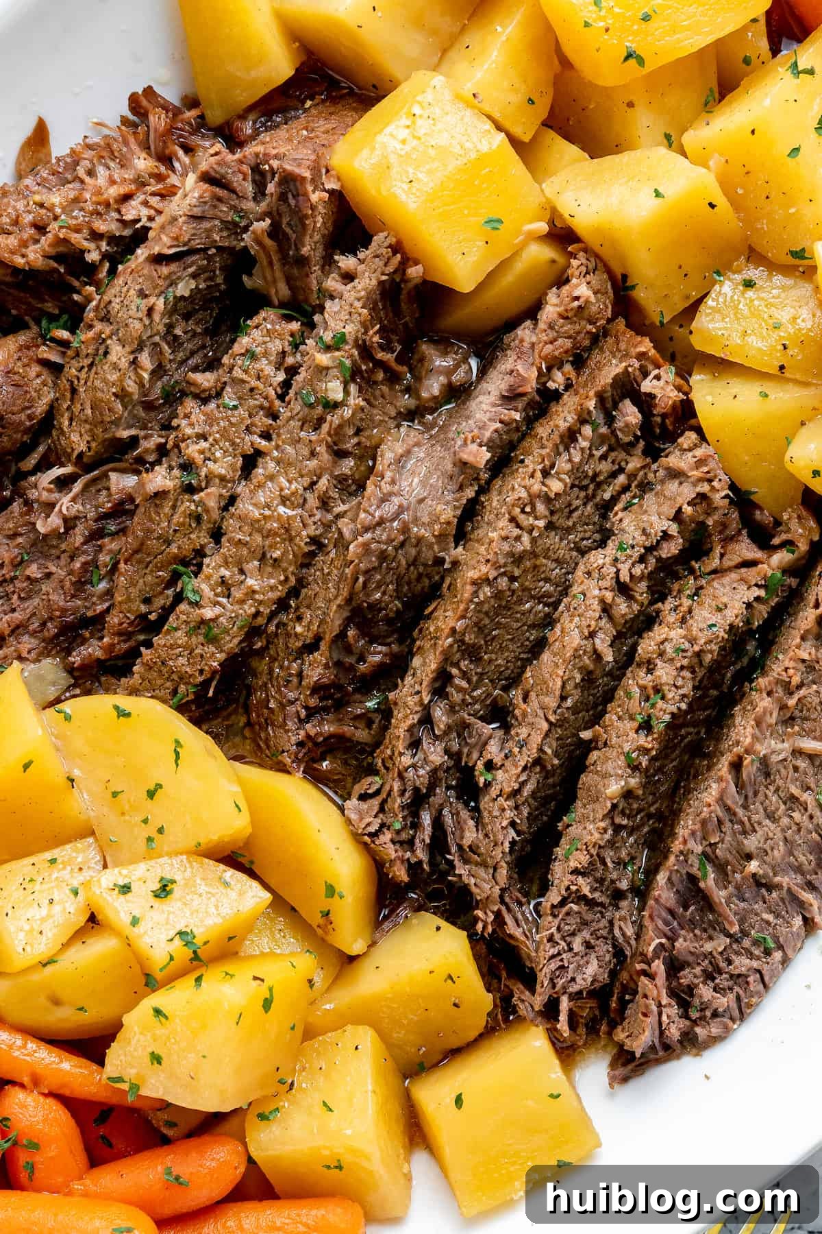Fork-Tender Instant Pot Pot Roast with Carrots and Potatoes 2 Pot roast with potatoes on a white plate, garnished with parsley.