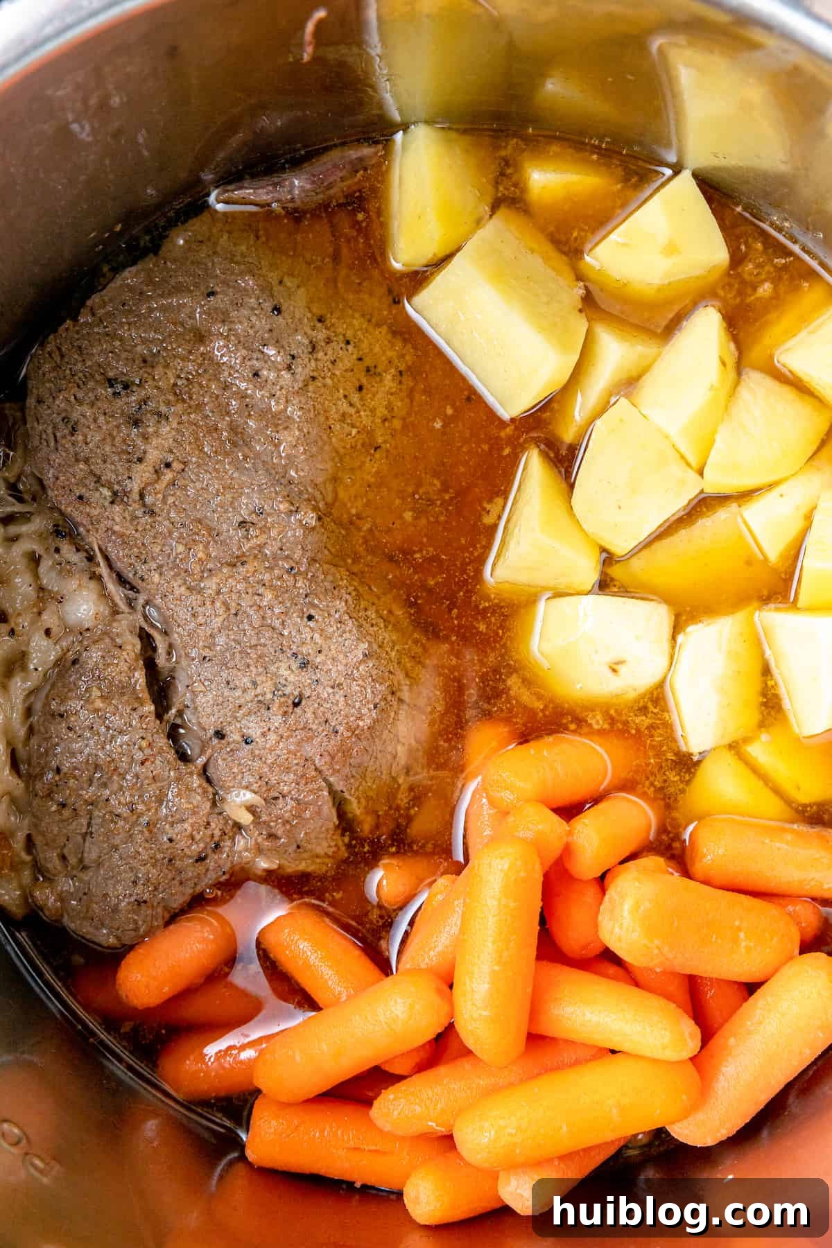 Fork-Tender Instant Pot Pot Roast with Carrots and Potatoes 6 Beef roast, carrots, and potatoes simmering in beef broth inside an Instant Pot.