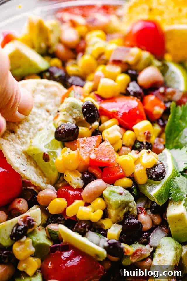 scooping up Cowboy Caviar with a tortilla chip, showing the vibrant colors