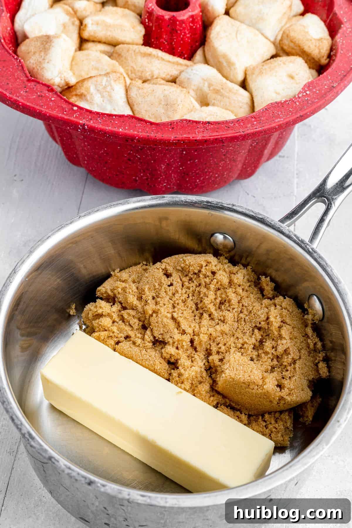 Gooey Cinnamon Pull-Apart Treat 4 A Bundt pan partially filled with coated biscuit dough pieces sits next to a small saucepan, where butter and brown sugar are melting together for the caramel sauce.