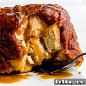 A baked monkey bread on a cake stand with some pieces removed.