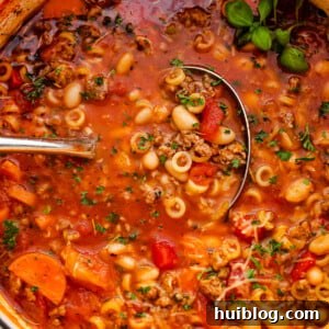Pasta Fagioli soup in a white Dutch oven with ladle inside the soup