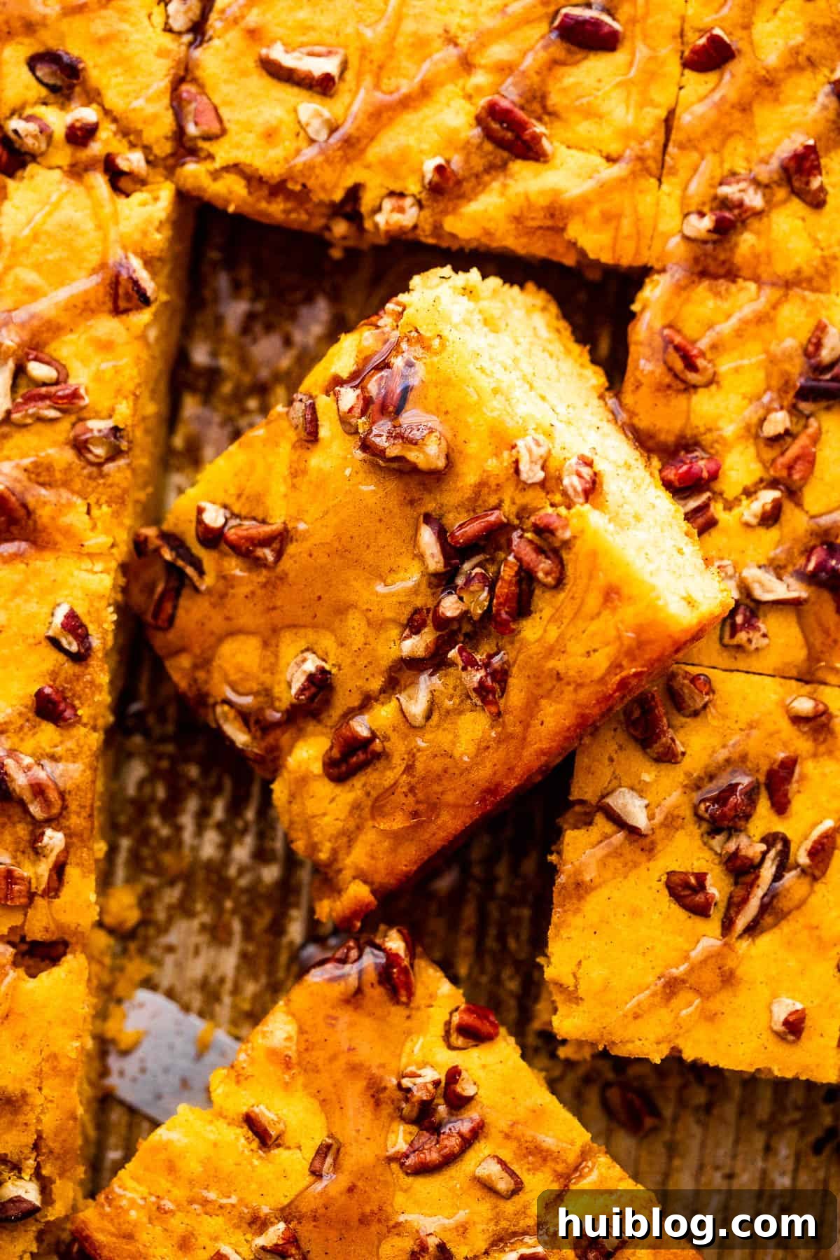 A close-up overhead shot of sliced sheet pan pumpkin pancakes, revealing their tender texture and a sprinkle of chopped pecans.
