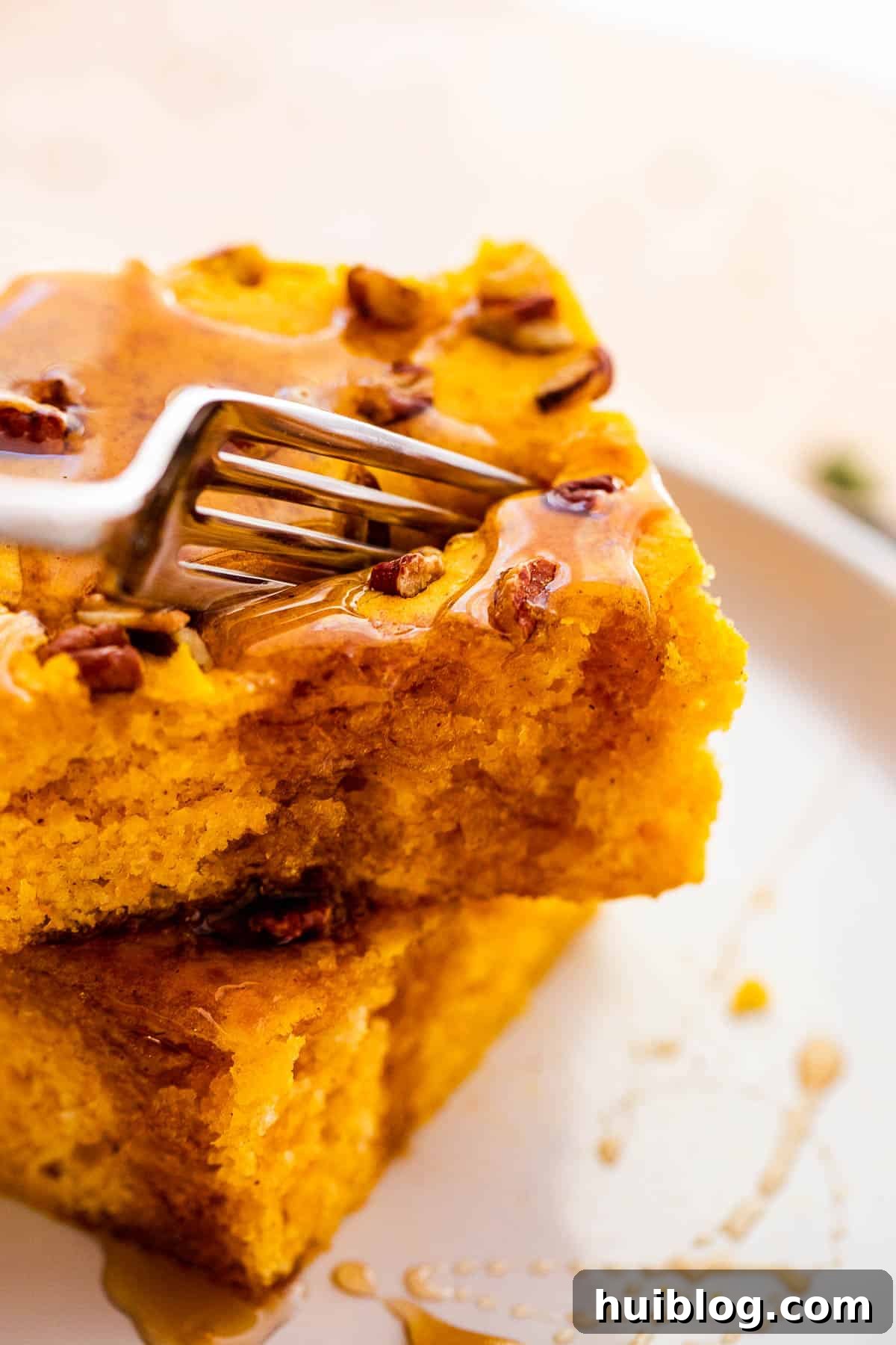 A fork cutting into a piece of golden sheet pan pumpkin pancake, perfectly browned and fluffy.