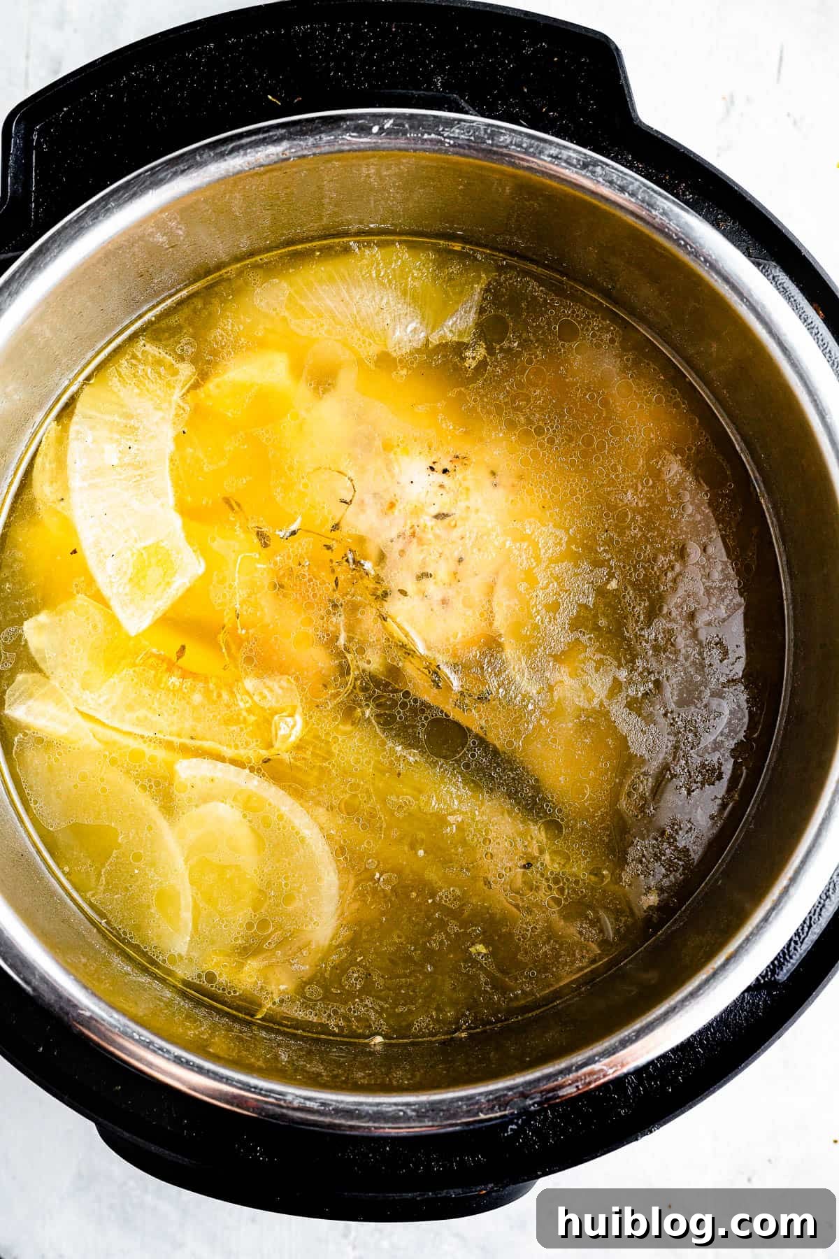 Liquid Gold: Instant Pot Chicken Broth 5 An overhead shot of the interior of an Instant Pot, filled with rich chicken broth, a cooked whole chicken, and scraps of vegetables, ready for straining.
