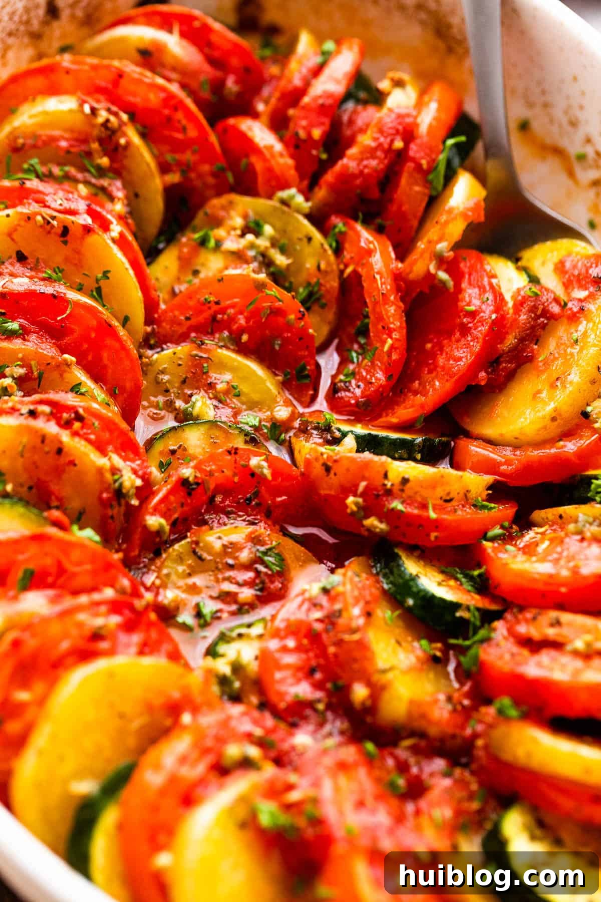 Sun-Kissed Zucchini Tomato Bake 3 Close-up view of meticulously arranged zucchini, tomato, and potato slices in a baking dish, showcasing the vibrant colors and fresh textures.