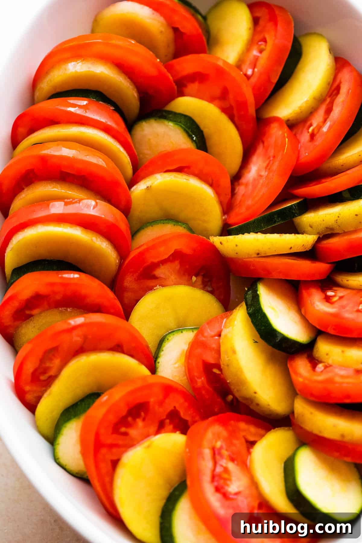 Sun-Kissed Zucchini Tomato Bake 4 Overhead shot illustrating the intricate arrangement of zucchini, tomato, and potato slices in a baking dish, highlighting the precise layering technique.