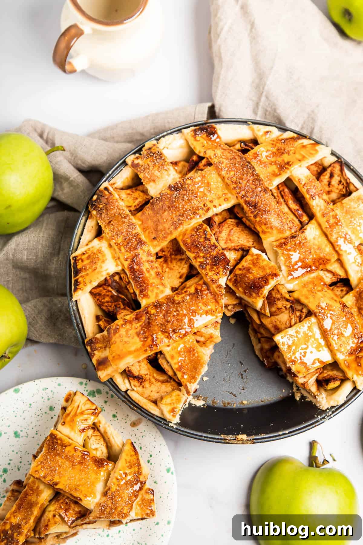 A freshly baked apple pie with one slice gracefully removed and placed on a small saucer nearby, showcasing the tender apple filling and flaky crust.