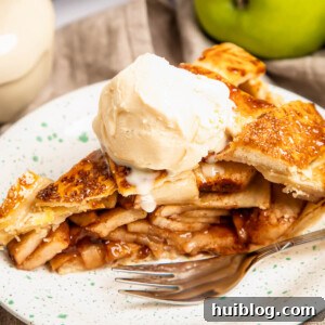 A delectable slice of apple pie crowned with a melting scoop of vanilla ice cream, presented on a white plate with a fork, ready to be enjoyed.