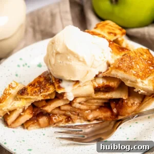 a slice of apple pie topped with ice cream on a plate with a fork