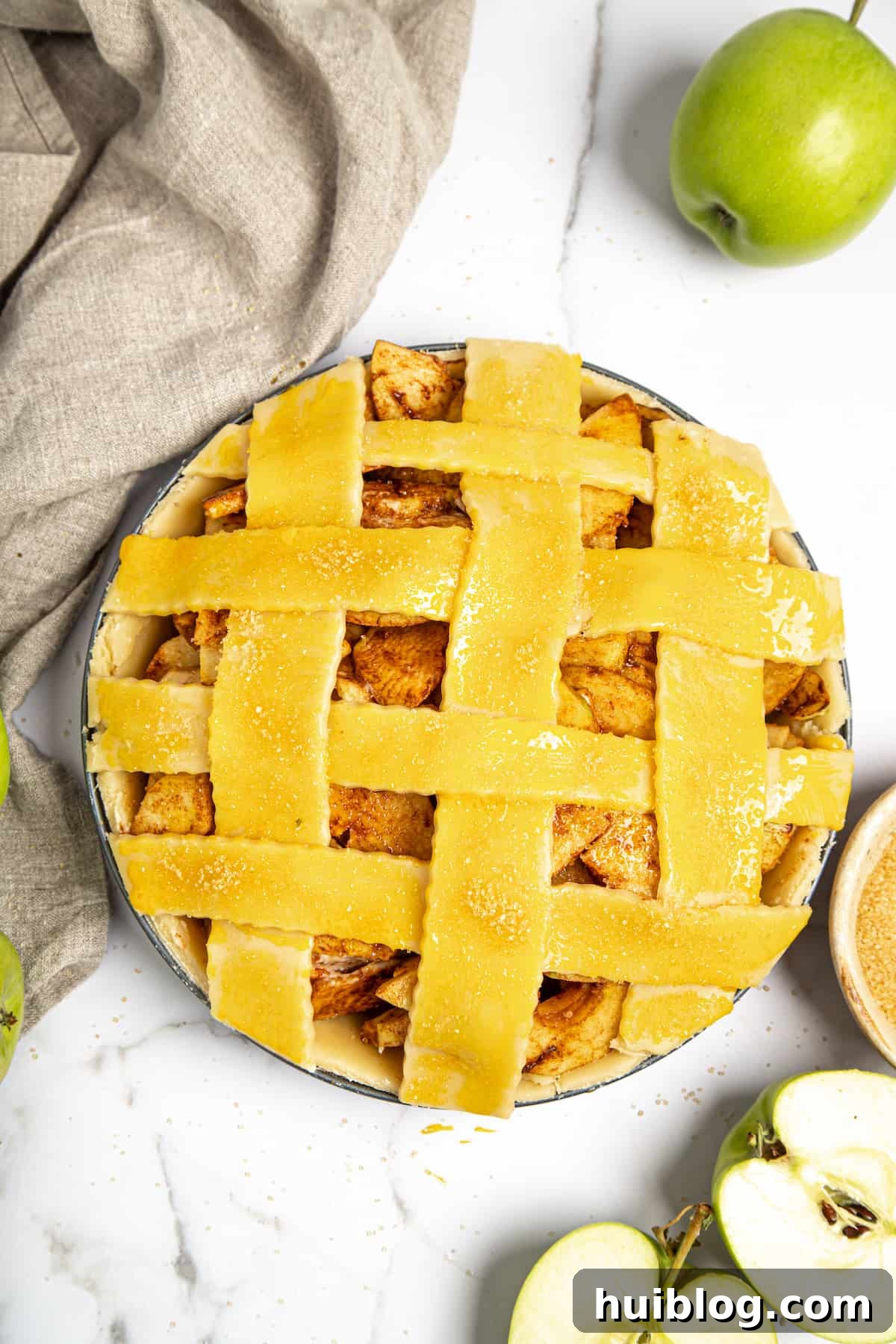 An unbaked apple pie with a perfectly woven lattice top, its edges crimped and sealed, awaiting baking.