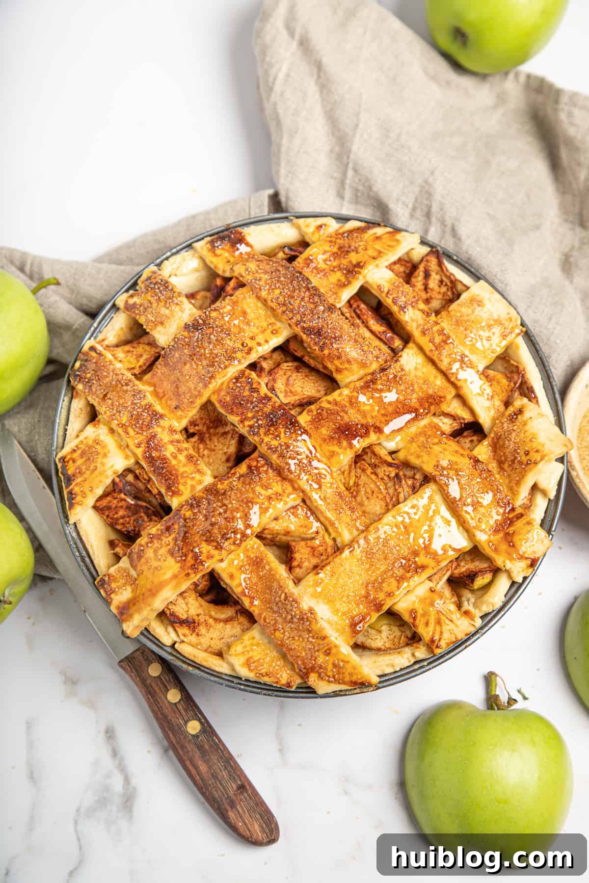 A freshly baked homemade apple pie with a golden-brown lattice top, sitting on a wire rack, steam gently rising.