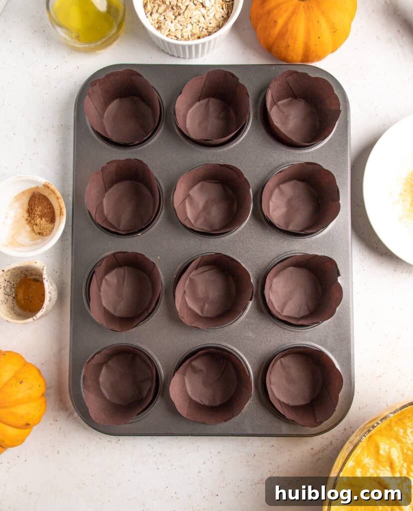A prepared muffin pan showcasing twelve rustic dark brown paper liners, waiting to be filled with batter.