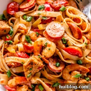 One Pot Jambalaya Pasta with chicken, sausage, shrimp, and linguine in a white bowl.