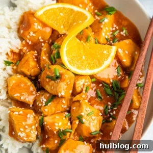 Overhead shot of orange chickn on a plate, garnished with an orange twist.