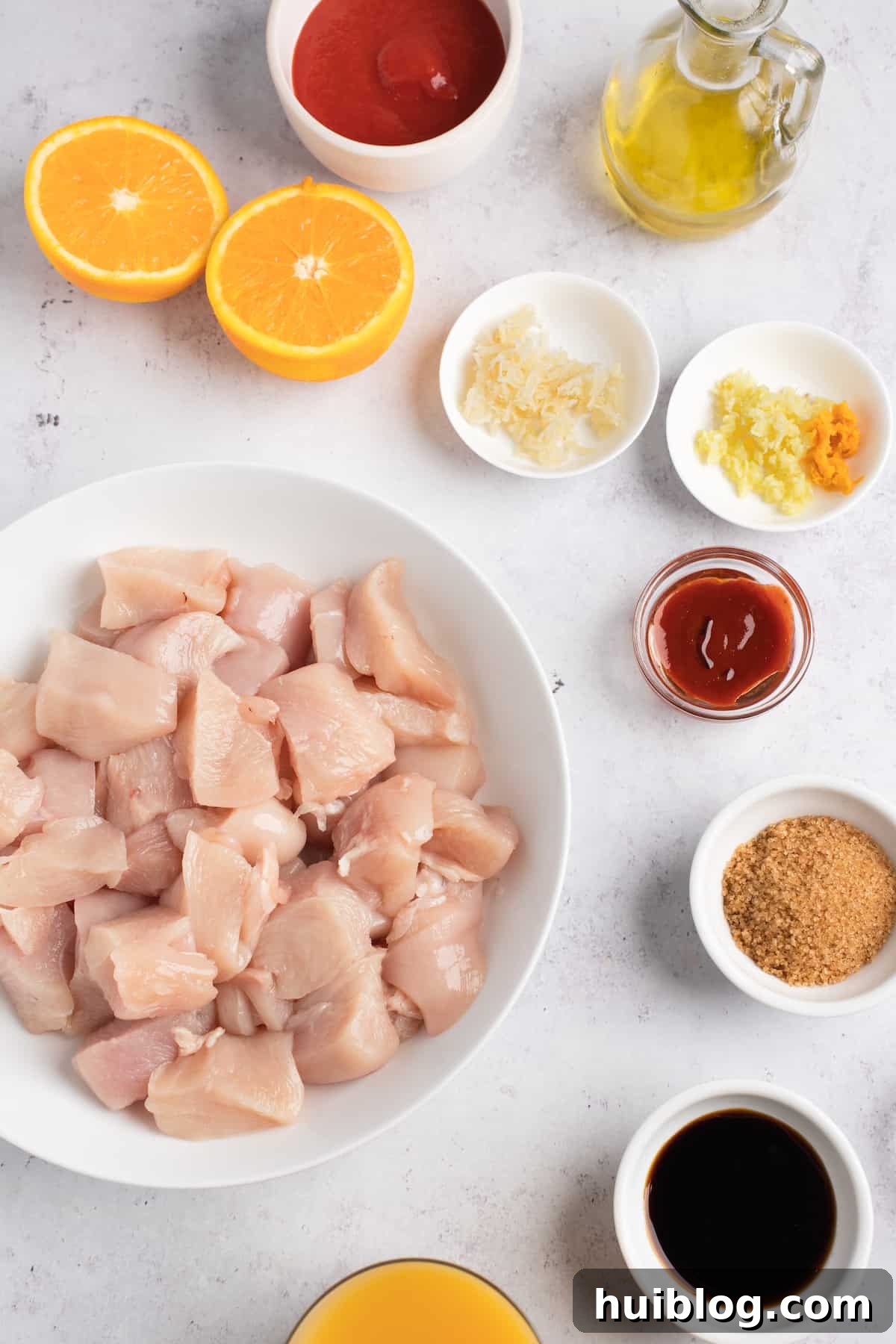 Clockwise from top: Tomato paste, oil, grated ginger, minced garlic and orange zest, sriracha sauce, soy sauce, orange juice, chicken, all ingredients ready for Instant Pot Orange Chicken.