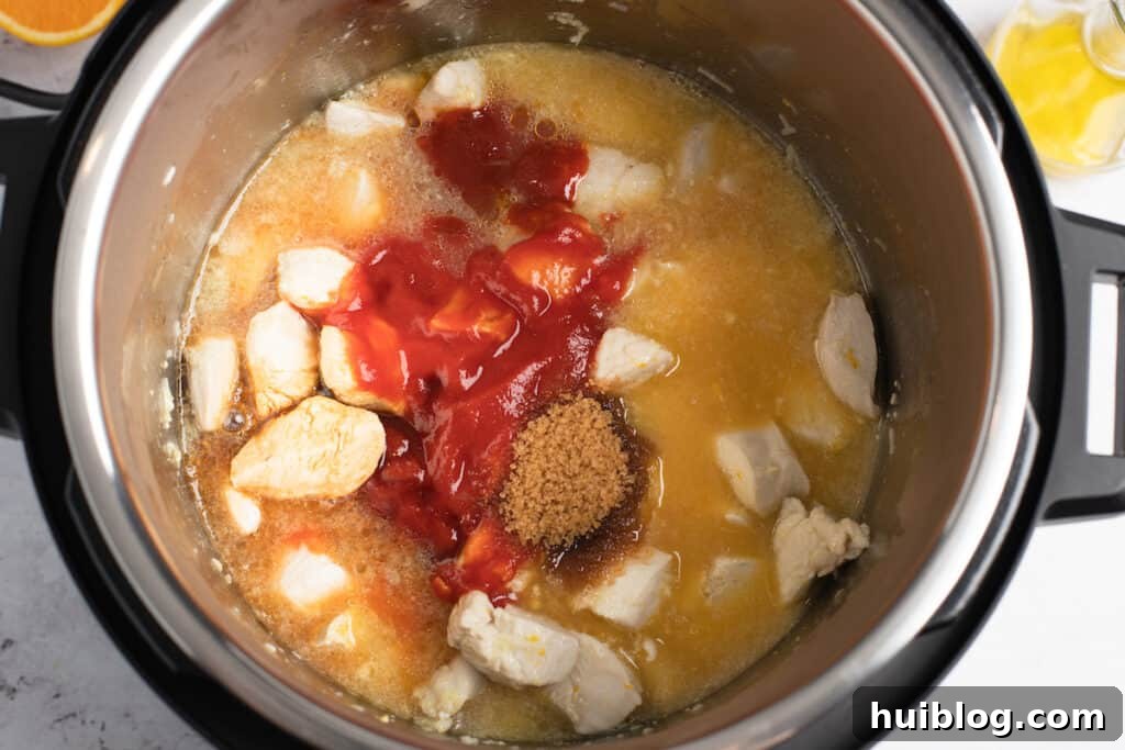 Chicken and various sauce ingredients being combined in the Instant Pot, showing the vibrant colors.