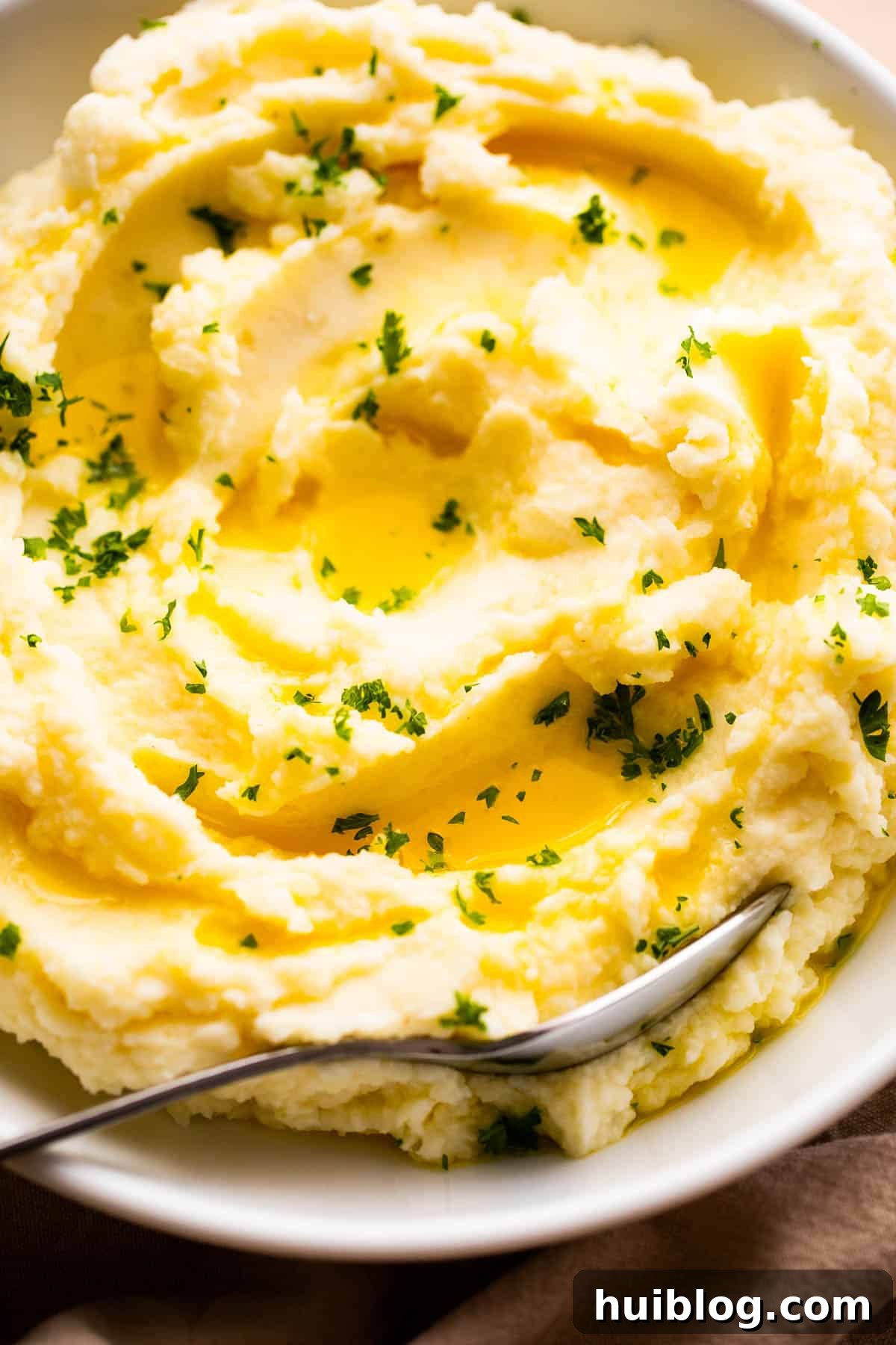 close up overhead shot of creamy mashed potatoes garnished with melted butter and parsley