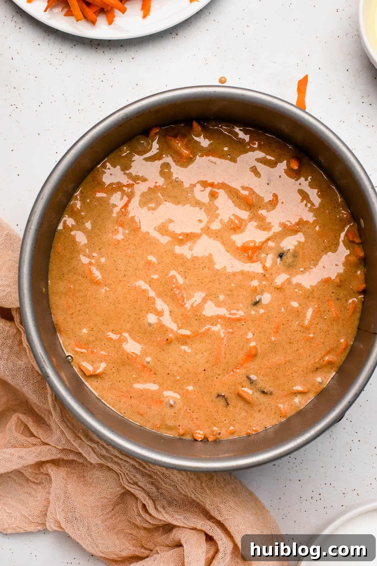 Overhead shot of rich carrot cake batter in a springform pan, ready for baking.
