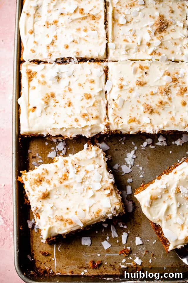 The ultimate frosted carrot cake in a sheet pan. A large, perfectly frosted carrot cake in a sheet pan, generously garnished with chopped walnuts and shredded coconut, promising deliciousness.