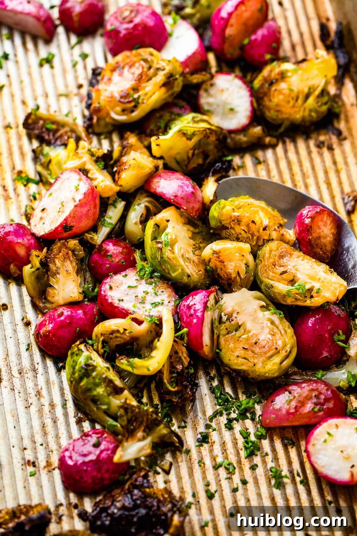Overhead view of a baking sheet filled with golden-brown, crispy roasted Brussels sprouts and radishes, perfectly cooked.