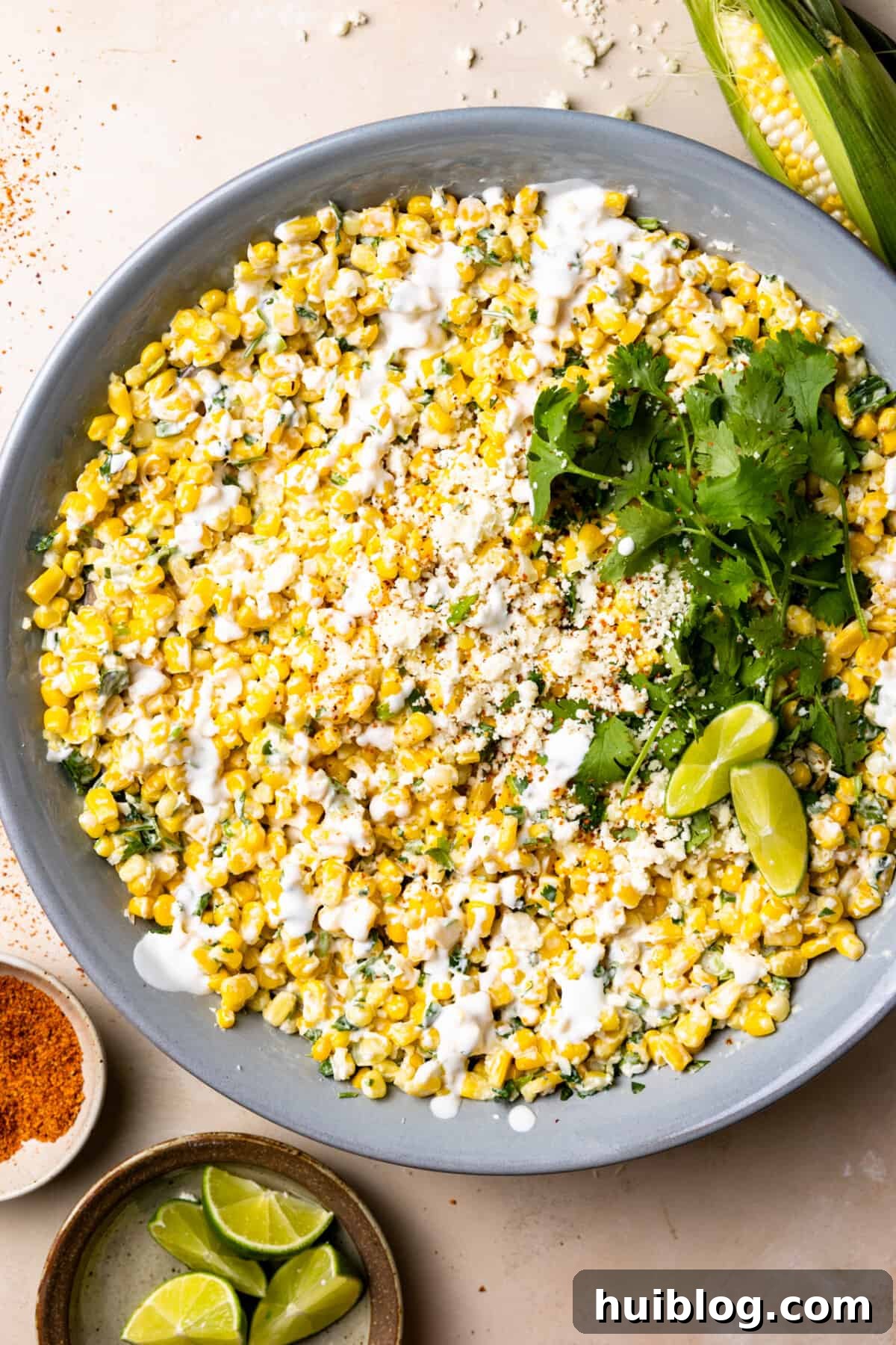 Effortless Slow Cooker BBQ Pulled Chicken 12 Mexican Street Corn Salad in a bowl topped with drizzled crema and crumbled cotija cheese.